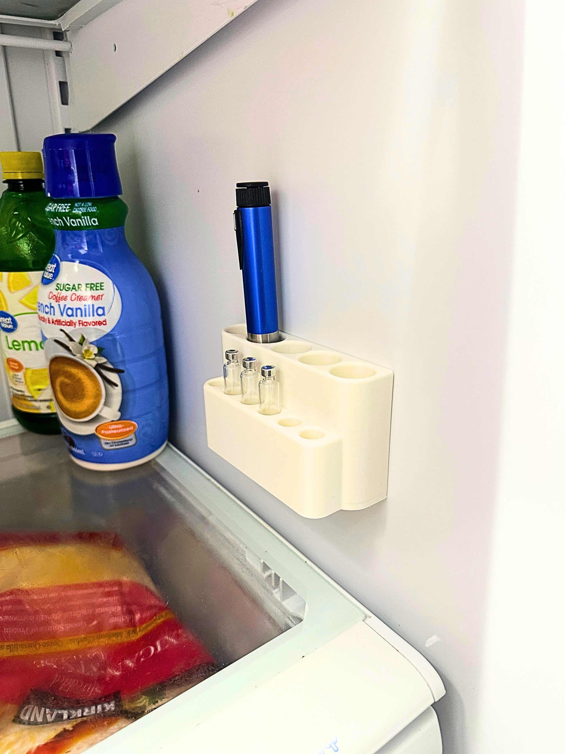 Fridge mount injection pen organizer mounted inside refrigerator holding blue pen and three cartridges